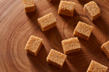 Brown cane sugar pieces on a slice, a plank of wood. With copy space.