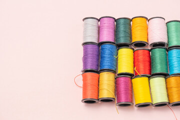 ピンクの背景のカラフルな縫い糸