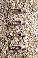 Line of wooden scoops on layer of rolled oats