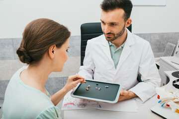 Hearing solution for adults. Audiologist chooses a hearing aid for a caucasian woman. Patient needs...