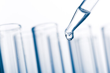 pipette with a drop and scientific laboratory test tubes in a research laboratory.