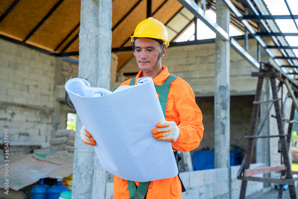 Poster engineer at work with blueprints in front of a construction site.