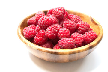 heap of fresh red raspberry in wooden plate isolated on white background