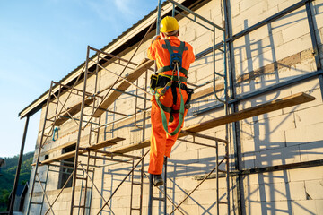 Construction worker wearing safety harness belt during working at high place at construction site.