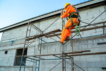 Fototapeta premium Construction worker wearing safety harness belt during working at high place at construction site.