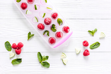 Ice tray with berries, lime and mint on white background top view