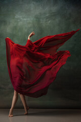 Character. Graceful classic ballerina dancing on dark studio background. Deep red cloth. The grace,...
