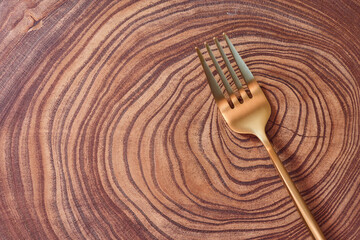 The golden fork lies on a slice of a tree. wooden table. With copy space.