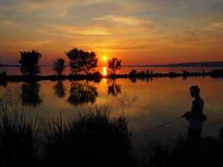 Balatonmáriafürdő, Hungary - June 27, 2020: Silhouette of a boy fishing at a canal in the south...