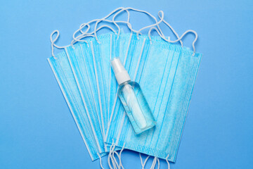 bottle of lotion, sanitizer or liquid soap and protective mask over blue background - flat layout