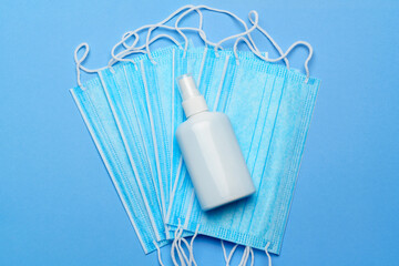 Fototapeta na wymiar bottle of lotion, sanitizer or liquid soap and protective mask over blue background - flat layout