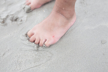 Sand on the beach and child's foot.
