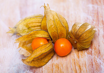 Physalis peruviana ripe fruits with dry leaves on wooden table