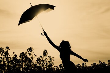 Unplugged free silhouette woman umbrella up to yellow sky. Nature girl at windy rainy day has adventure wanderlust. Wonderful scene of imagination power and departure to new horizons in youth