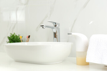 Fototapeta na wymiar Modern automatic soap dispenser near sink in bathroom, closeup