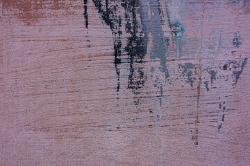 Colored cement plaster with traces of sanding and scratches, spilled with paint on the wall.