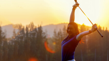 Golfer woman cheerful happy and relax with a golf in the golf club in the sunny and evening sunset...