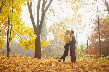 Young happy couple relaxing and loving in the autumn forest at sunset.