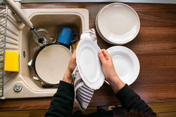 Woman wiping dishware with cotton towel in kitchen