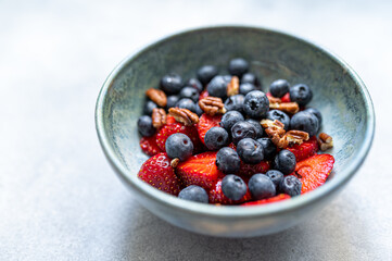 Bowl of healthy fresh berries salad on light blue background