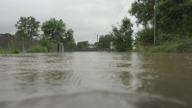 Flooded street during floods. The camera is level with the water. Water flooded the road and the fence of a private house. It rains and the water level rises. Limnitsa River Ukraine.