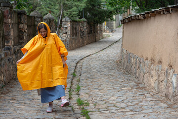 happy girl in yellow rain coat in village