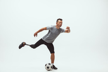 Athlete with disabilities or amputee on white studio background. Professional male football player with leg prosthesis training in studio. Disabled sport and healthy lifestyle concept. Achievements.