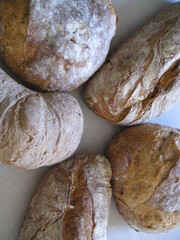 conjunto de panes artesanos (trigo, centerno, espelta) unidos en estrella sobre mantel blanco.  vista cenital