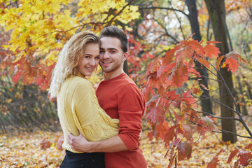 Fototapeta premium Young happy couple relaxing and loving in the autumn forest at sunset.