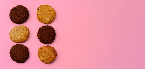Chocolate cookies and oat cookies on pink background with copy space