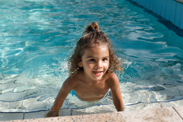 Fototapeta na wymiar Bambina Brasiliana si diverte a fare il bagno in una piscina