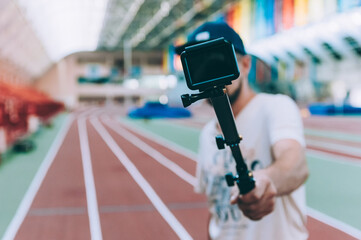 Blogger in the stadium shoots video with action camera.