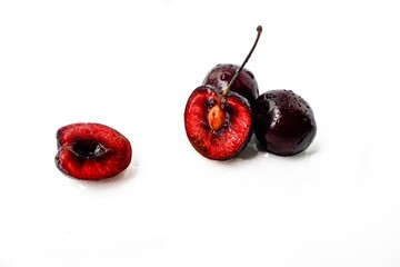 Bright ripe juicy cherry cut in half with a bone inside on a white background.