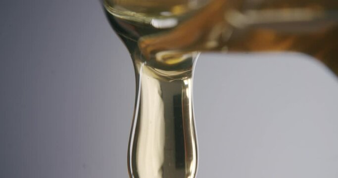 Drops of honey dripping out of a honey jar. Soft commercial light. Honey glowing golden.