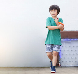 Outdoor portrait of active kid boy walking  Happy Child carrying toy playing outside in sunny day summer. Positive children concept