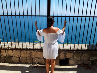 Kobieta w białej sukience na tle błękitnego krajobrazu, Gaeta, Italia. - obrazy, fototapety, plakaty