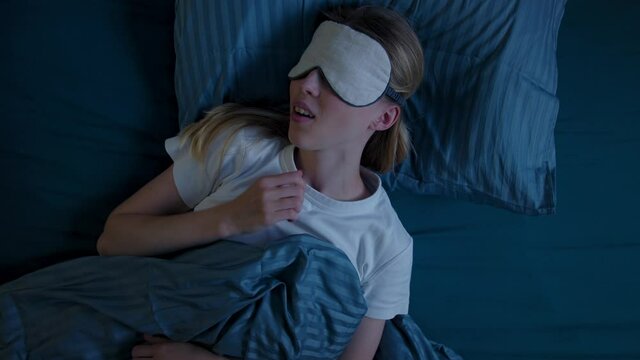 Top View Young Woman In Bed At Night Having Terrible Nightmare, Screaming In Sleep, She Wakes Up Scared And Covered In Sweat. Looks At Camera, Exhales And Falls Asleep Pulling Sleep Mask Over Eyes