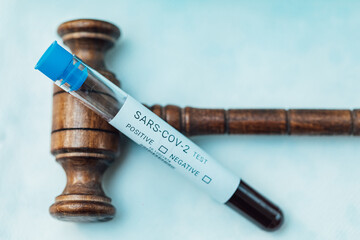 Test tube with blood to do COIVD test supported by judge's gavel
