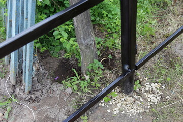 Mounting of pillars supporting the base of a new metal fence, strengthening with pebble