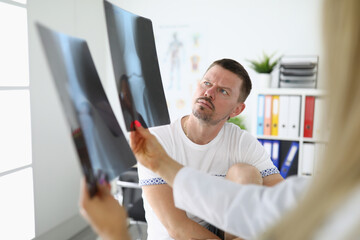Naklejka na ściany i meble Man in medical office is looking at x-rays with doctor. Medical care concept