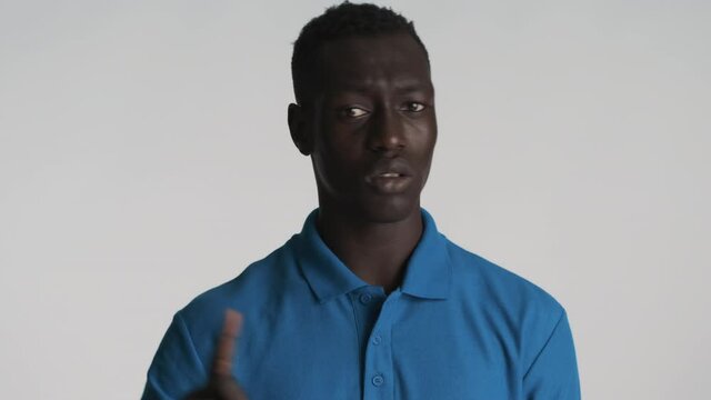 Young confident African American man waving head showing no gesture on camera over gray background. Disagreeing expression