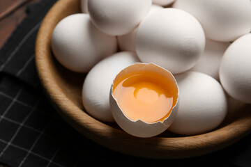 Many fresh raw chicken eggs in bowl on table, closeup