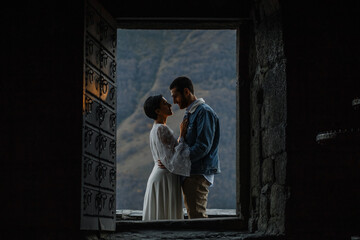 Young Georgian couple posing in the mountains. Boho wedding in Georgia. Evening setting sun. Blue...