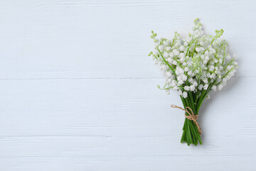 Beautiful lily of the valley flowers on white wooden table, top view. Space for text