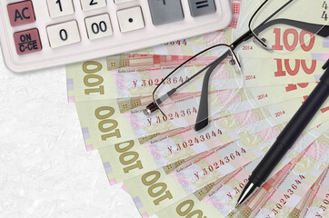 100 Ukrainian hryvnias bills fan and calculator with glasses and pen. Business loan or tax payment...