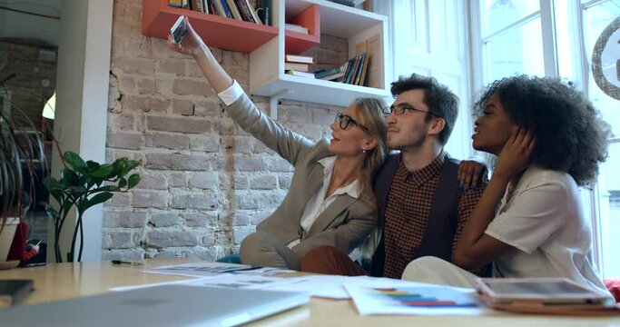 Group of multirace colleagues are taking selfies and making different faces at the workplace. Office concept. 4k.