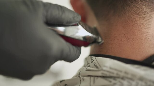 Close up electric trimmer shaver shaving asian male customer, Asian young man Getting Hair Cut, male barber, re-open business, rear view, sharp edge cutting Short hair man, barber wear black gloves