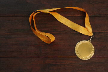 Gold medal on wooden background, top view. Space for design