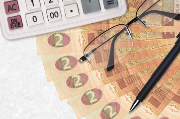 2 Ukrainian hryvnias bills fan and calculator with glasses and pen. Business loan or tax payment...