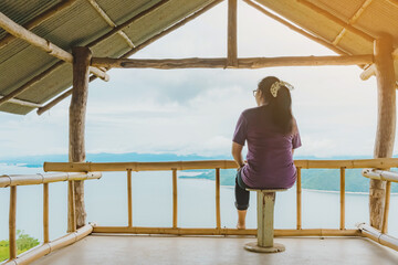 Back view of woman enjoy with beautiful scenery view of nature with a large reservoir above the Srinagarind Dam at Rai Ya Yam view point in Si Sawat District, Kanchanaburi Thailand.